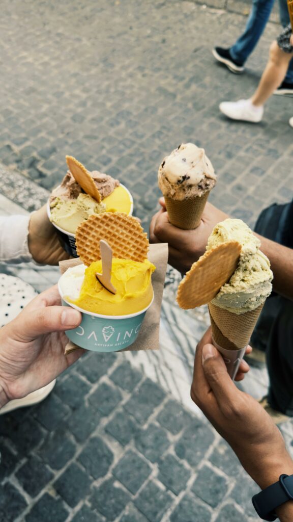 A group of people holding diverse ice cream cones with wafers on a cobblestone street.
